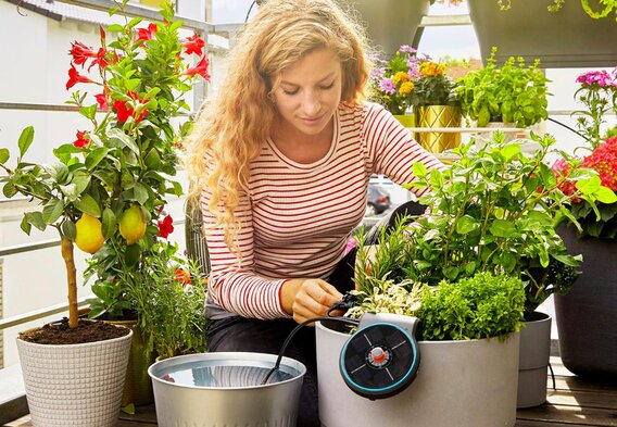 Eine Frau pflanzt Blumen auf dem Balkon.  | © GARDENA
