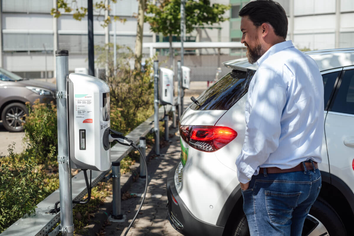 Mann lädt Elektroauto an der E-Ladesäule auf